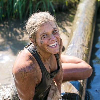 woman jumping over log during mud race