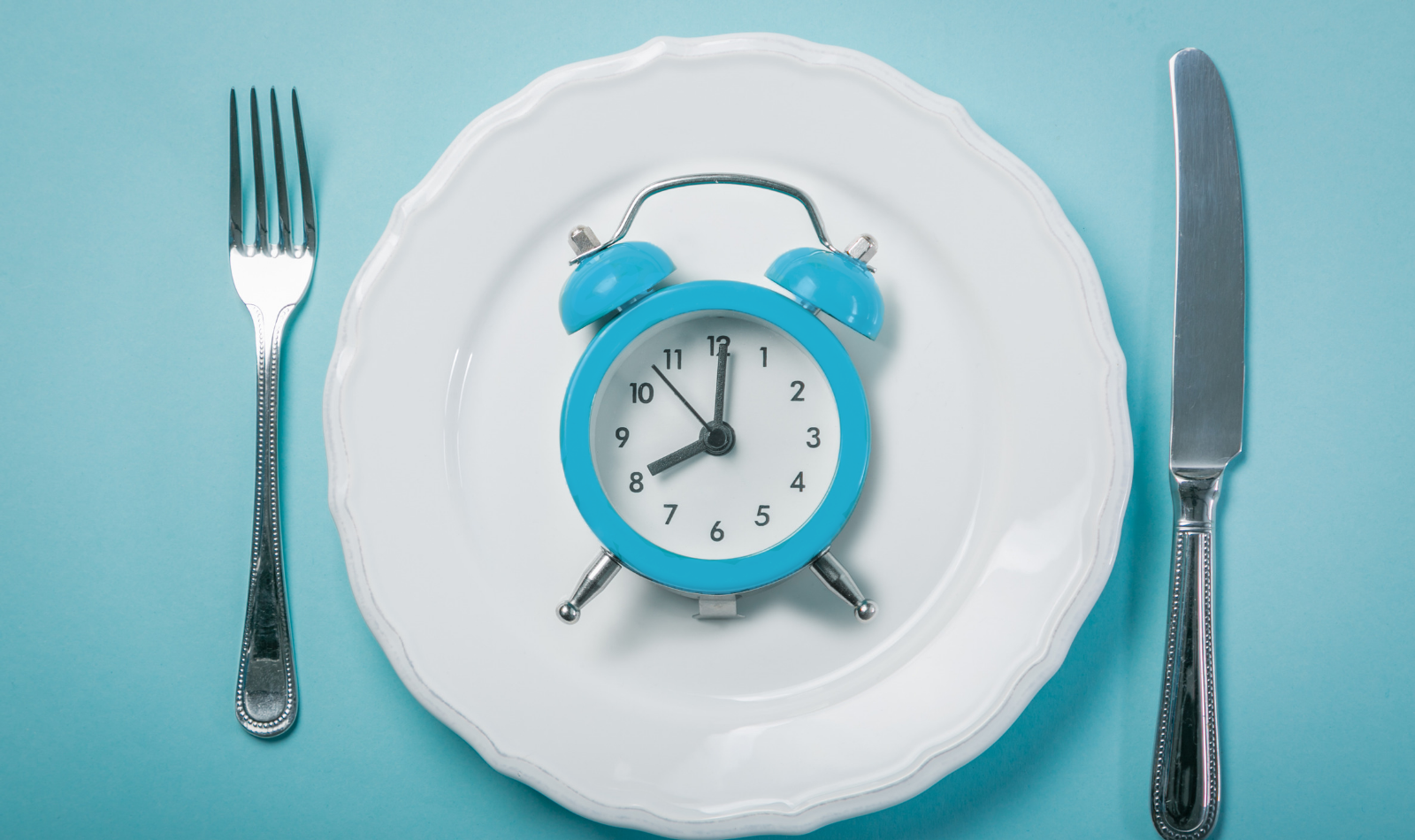 photo of a clock on a plate with a fork and knife