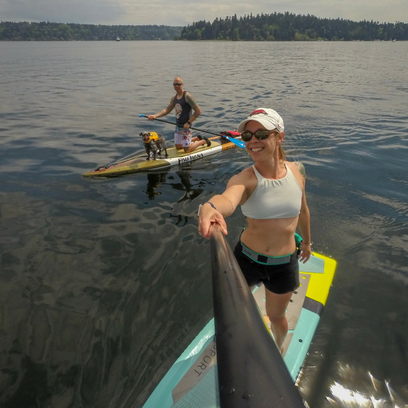 woman standing on paddle board in a lake taking a selfie